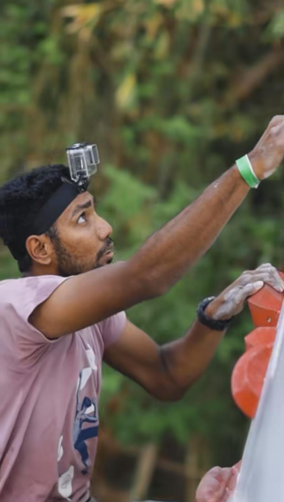 Manoj reaching for a hold on a climbing wall