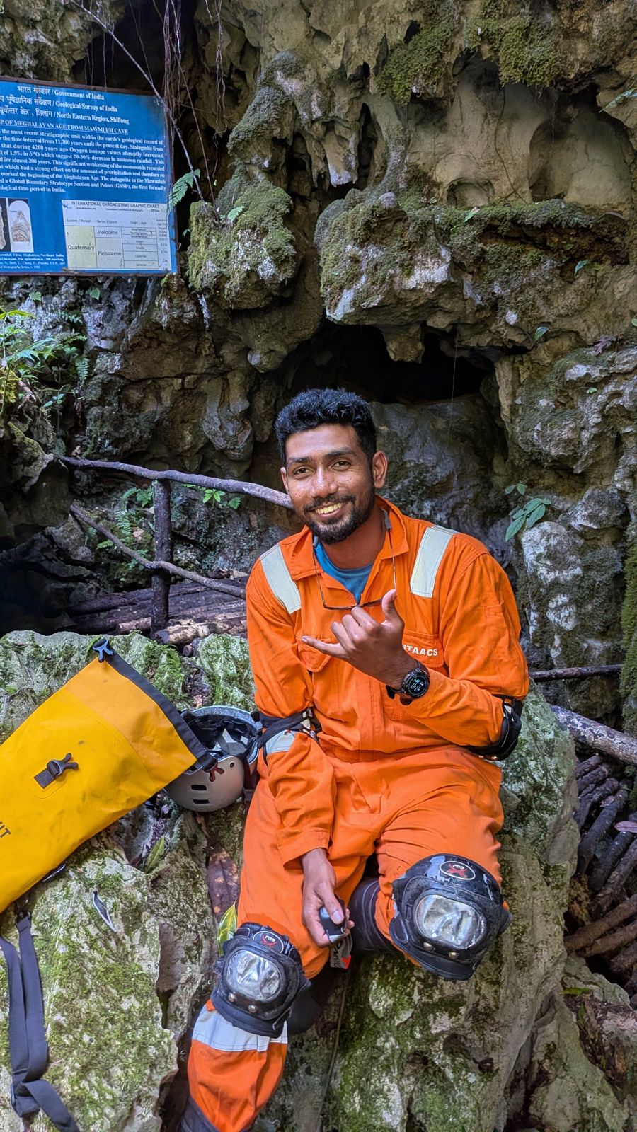 Manoj in orange caving suit at the mouth of Mawmluh Cave